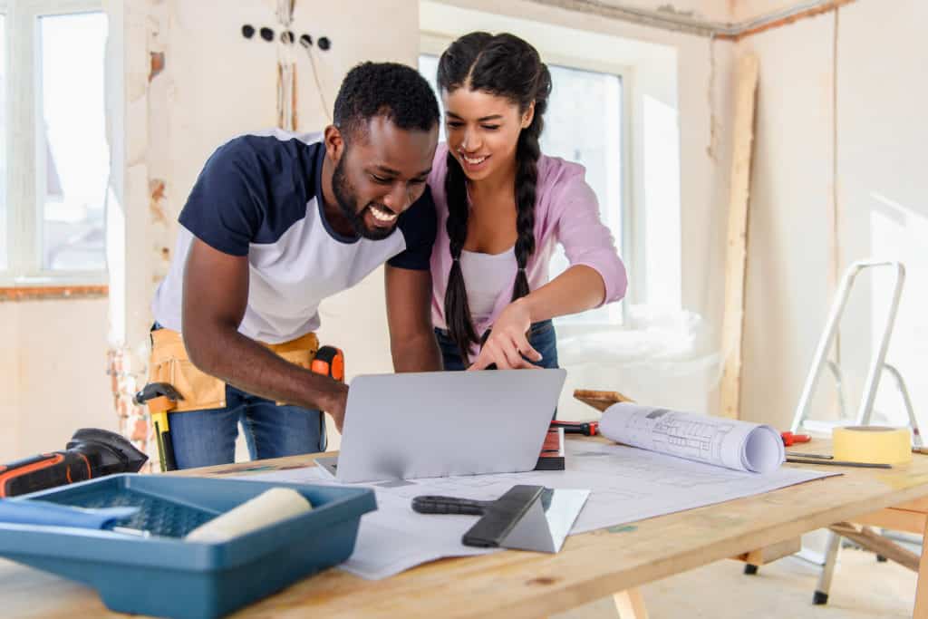 A couple remodling house, looking at plans on laptop