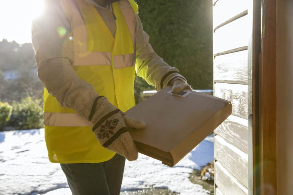 person delivering an ecommerce package in the snow to illustrate December Signifyd Pulse data