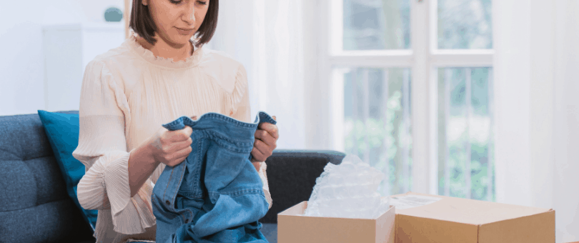 A woman looking dejectedly at blue jeans to illustrate a post on return fraud