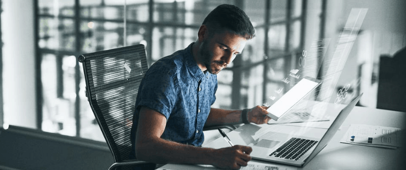 man writing code in a modern glass-filled office